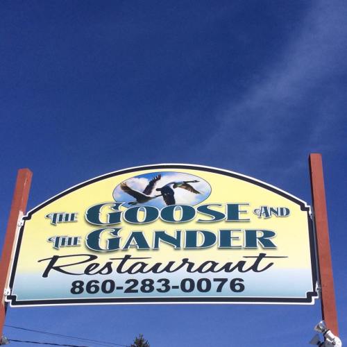 Sign for "The Goose and The Gander Restaurant" against a clear blue sky, featuring a graphic of birds.