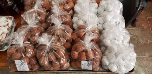 Bags of assorted round treats, some brown and some white, neatly arranged on a wooden table.