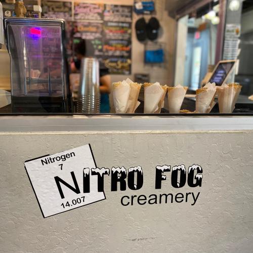 A counter at Nitro Fog Creamery with nitrogen-themed decor and ice cream cones ready for serving.