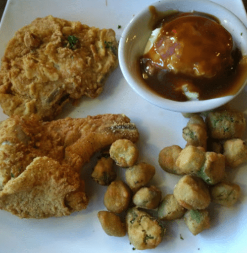 A plate with fried chicken, a bowl of gravy with mashed potatoes, and a side of fried okra.