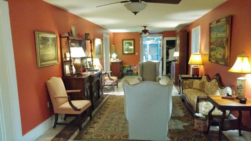 Cozy living room with orange walls, vintage furniture, and warm lighting, featuring a rug and decorative artwork.