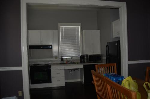 A modern kitchen with white cabinets, black appliances, and a dining area with wooden chairs and a table.