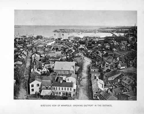 Bird's-eye view of Annapolis, showcasing buildings and Eastport in the distance, with a body of water visible.