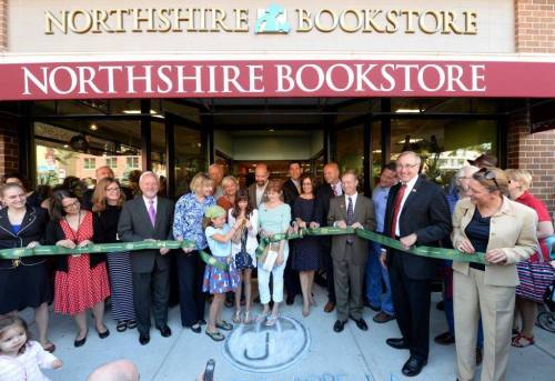 A group of people gathers outside Northshire Bookstore for a ribbon-cutting ceremony, celebrating its opening.