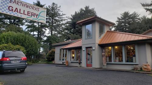Exterior of Earthworks Gallery, featuring a modern building with a copper roof and large windows, surrounded by trees.