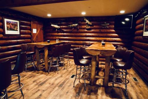 Cozy log cabin interior with wooden tables, bar stools, and fish decor on the walls. A TV is mounted in the corner.