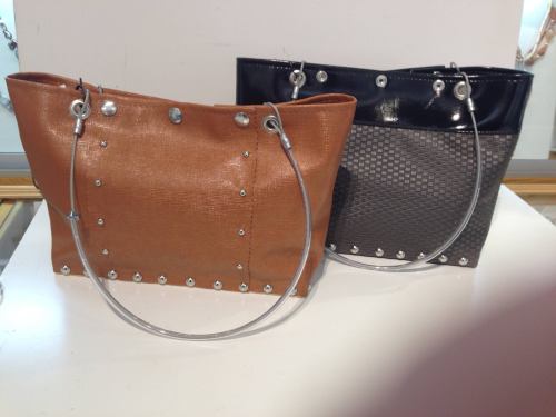 Two stylish handbags: one in brown with silver studs and the other in black with a textured pattern and clear handles.