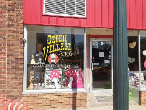 Storefront of "Czech Village Antiques" featuring colorful displays and collectibles in the window.