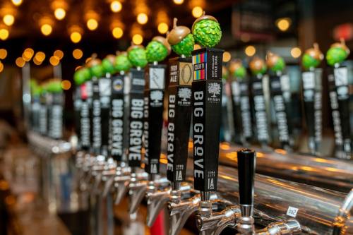 A row of beer taps with "Big Grove" labels, set against a backdrop of warm, glowing lights.