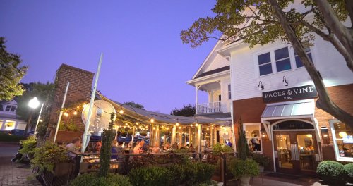 A cozy restaurant exterior at dusk, with string lights and diners enjoying the outdoor seating area.