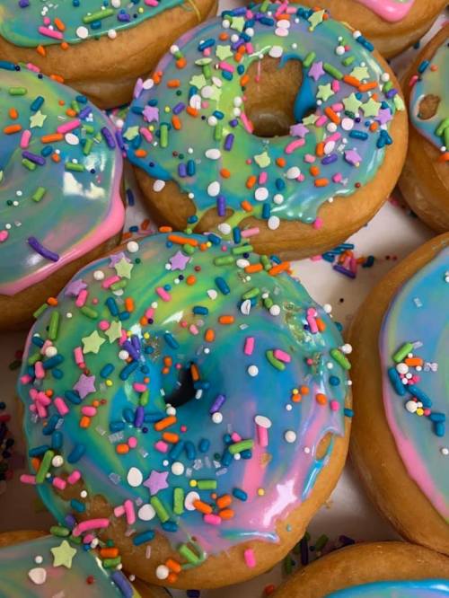 Colorful donuts with vibrant blue and pink icing, topped with sprinkles and star-shaped confetti.