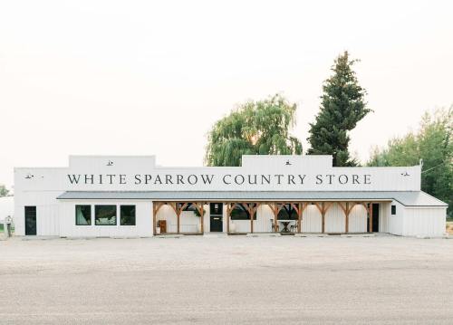 Exterior of White Sparrow Country Store, featuring a white building with large windows and a welcoming entrance.