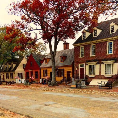 Historic buildings with autumn foliage, featuring red and yellow leaves, lined along a cobblestone street.