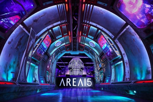 Futuristic interior of AREA15, featuring vibrant lighting, digital displays, and a central geometric structure.
