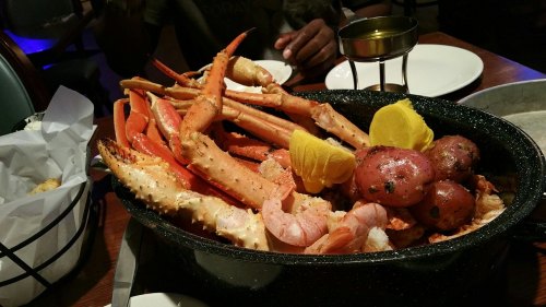 A large seafood platter featuring crab legs, shrimp, and potatoes, garnished with lemon slices.