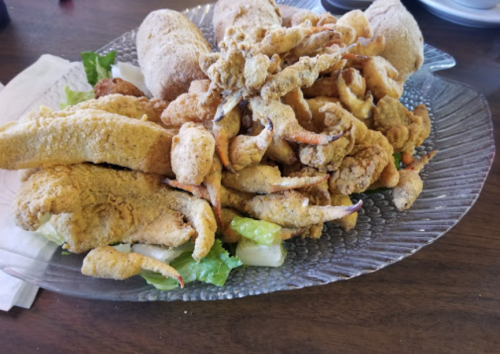 A platter of assorted fried seafood, including crab claws and fish, served on a bed of lettuce.