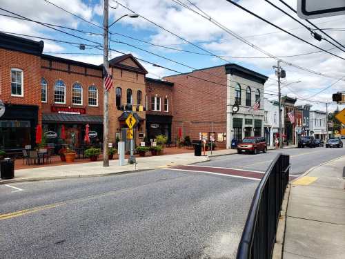 A charming street scene with shops, flags, and a clear blue sky, showcasing a small-town atmosphere.