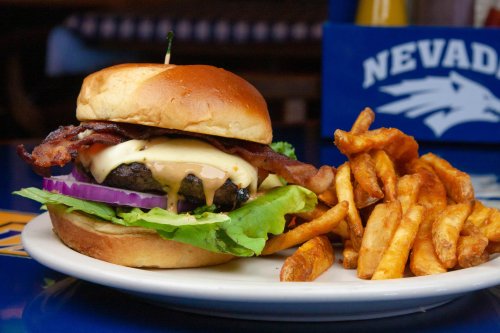 A juicy burger with bacon, cheese, lettuce, and onion, served with a side of crispy sweet potato fries.
