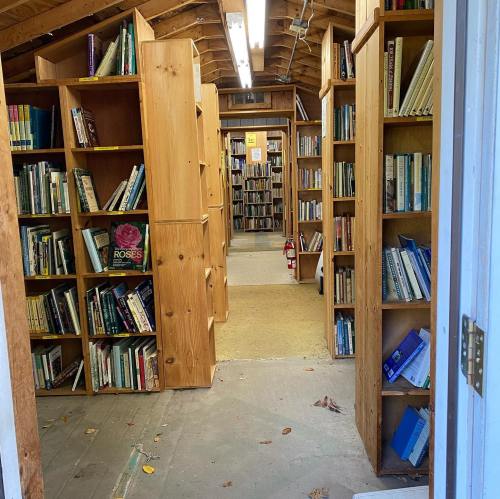 A cozy library interior with wooden bookshelves filled with books, leading to a well-lit reading area.