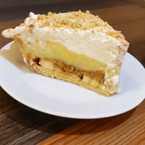 A slice of layered dessert with cream, fruit filling, and crumbled topping on a white plate.