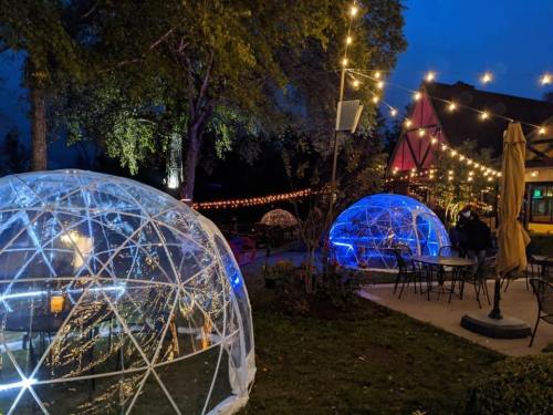 Two illuminated outdoor igloos surrounded by string lights in a cozy garden setting at night.