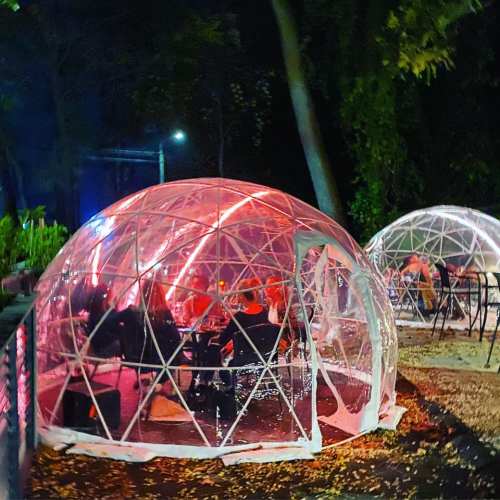 A cozy outdoor dining area with illuminated igloo-like structures surrounded by trees at night.