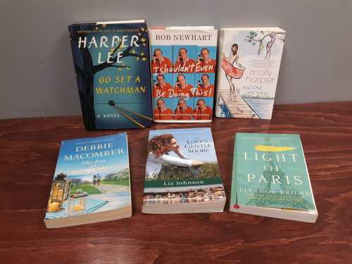 A collection of six books displayed on a wooden surface, featuring various authors and titles.