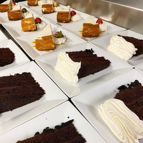 Plates of chocolate and pumpkin cakes, garnished with whipped cream and strawberries, arranged neatly on a table.