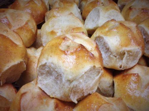 Freshly baked golden-brown rolls piled together, showcasing a soft, fluffy interior.