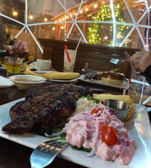 A beautifully plated steak with salad and sides, set on a table with festive lights in a cozy dining space.