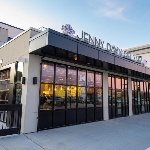 Exterior of the Jenny Davitchar building, featuring large windows and a modern design at sunset.