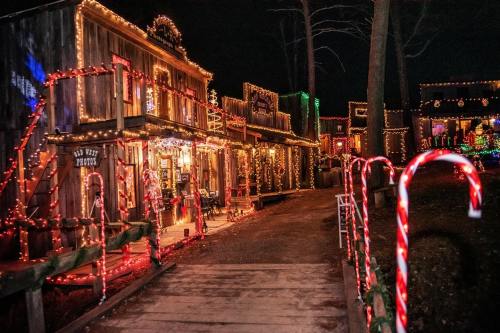 A festive street scene at night, featuring buildings adorned with colorful holiday lights and candy cane decorations.