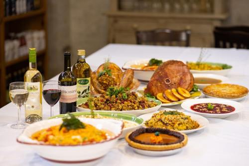 A festive table spread with various dishes, including ham, turkey, stuffing, wine, and desserts.