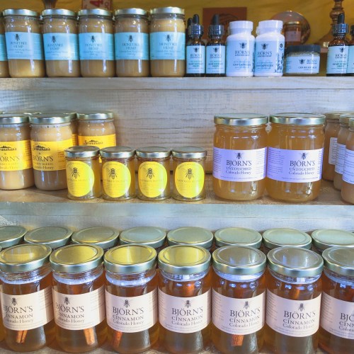 A display of various jars of honey and honey products on wooden shelves, labeled with "Bjorn's" branding.