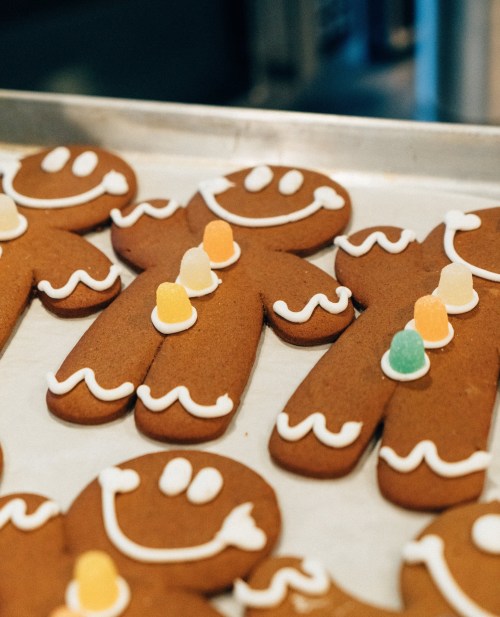 A tray of decorated gingerbread cookies shaped like smiling gingerbread men, adorned with colorful candy.