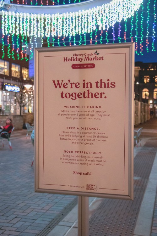Sign at Cherry Creek Holiday Market outlining COVID-19 safety protocols, including mask-wearing and social distancing.