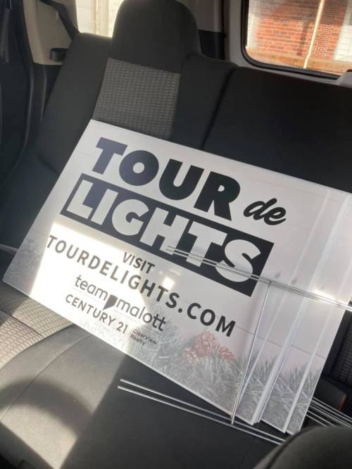 Sign for "Tour de Lights" displayed on a car seat, promoting the event and website tourdelights.com.