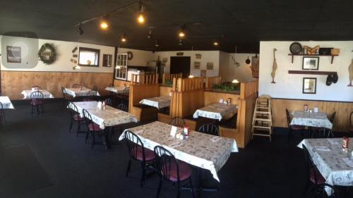 Interior of a cozy restaurant with tables set for dining, wooden decor, and warm lighting.
