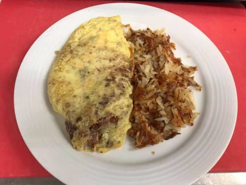 A plate with a fluffy omelet and a side of crispy hash browns on a white dish.