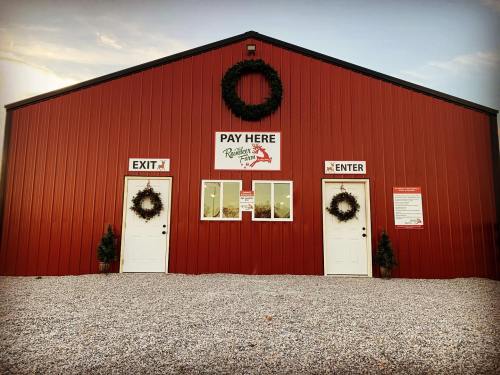 Red barn with two doors labeled "Enter" and "Exit," decorated with wreaths, and a sign that says "Pay Here."