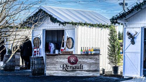 A rustic bar with a Renault logo, surrounded by festive decorations and bottles, set in a charming outdoor venue.