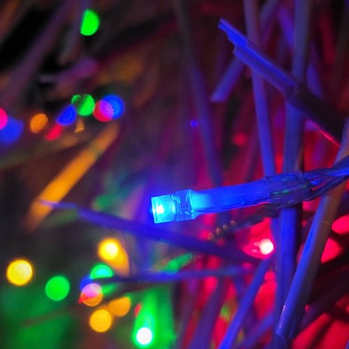 Close-up of colorful Christmas lights intertwined with straw, creating a festive and vibrant atmosphere.
