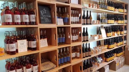 Shelves filled with various bottles of cider and beverages, with signs indicating discounts on full cases.