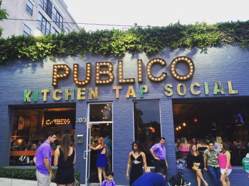 Exterior of Publico Kitchen Tap Social, featuring a vibrant sign and a lively crowd outside the restaurant.