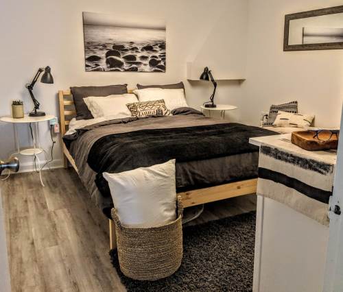 Cozy bedroom featuring a wooden bed, gray bedding, bedside tables, and decorative elements in a minimalist style.