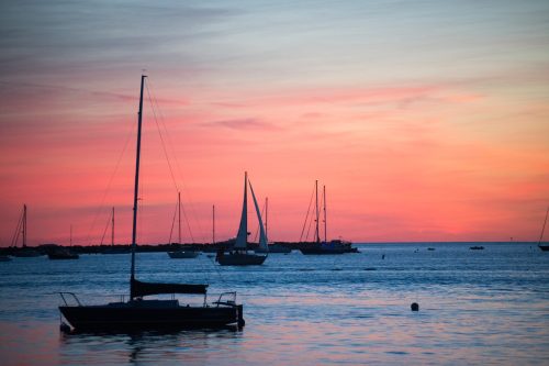 A tranquil sunset over the water, with sailboats silhouetted against a colorful sky.