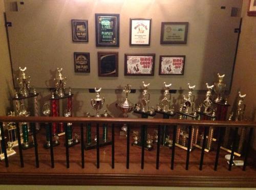 A display of various trophies and awards on a shelf, showcasing achievements in competitions.