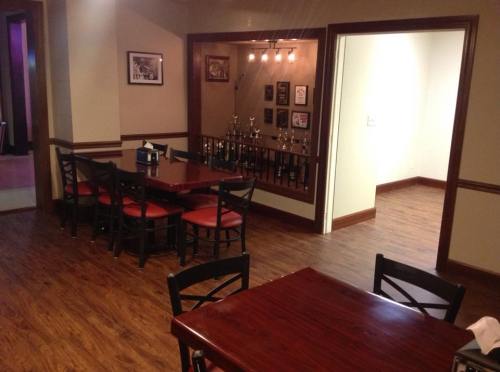 A cozy restaurant interior featuring wooden tables, chairs, and a display of trophies in a well-lit area.