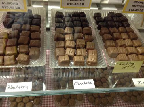 A display of assorted chocolates and truffles in a glass case, labeled with flavors like raspberry and peanut butter.