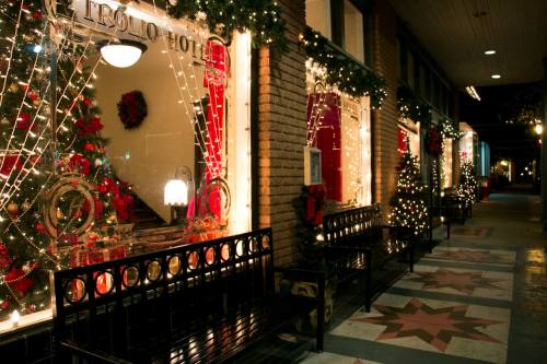 Festively decorated storefronts with Christmas lights and trees, creating a warm holiday atmosphere at night.